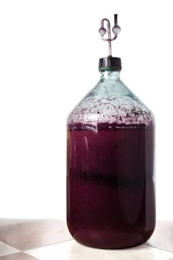 Kırmızı ev yapımı şarap yapma süreci. 20 litrelik cam şişe ve mantarda hava kilidi var. Fermantasyon süreci.