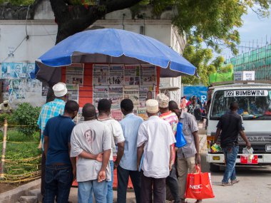 Zanzibar Kasabası, Tanzanya, Doğu Afrika, 17 Haziran 2017. Yerel halk şehir merkezindeki bir stantta gazete okuyor..