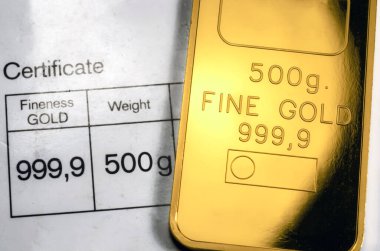 Minted gold bar weighing 500 grams on paper certificate background. Gold ingot with assay certificate. clipart