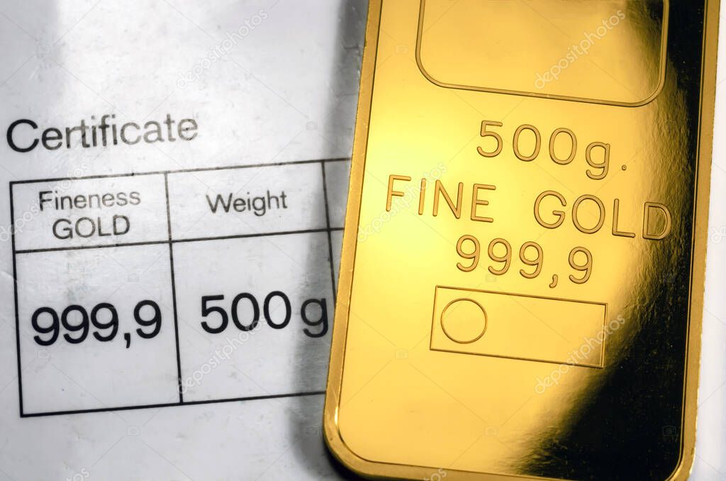 Minted gold bar weighing 500 grams on paper certificate background. Gold ingot with assay certificate.