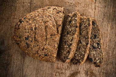 Kepek, keten, kurutulmuş meyve, tohum, fındık ve diğer malzemelerden yapılmış vejetaryen ekmeği ahşap doku arka planında. vejetaryen yemeği.