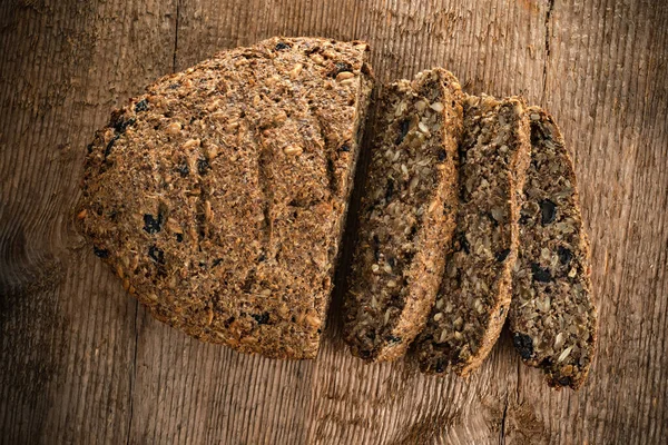 Kepek, keten, kurutulmuş meyve, tohum, fındık ve diğer malzemelerden yapılmış vejetaryen ekmeği ahşap doku arka planında. vejetaryen yemeği.