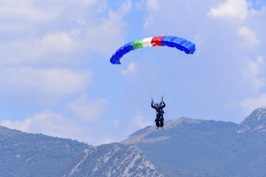 paraşütçü mavi gökyüzü, arka planda karşı dağlar iner