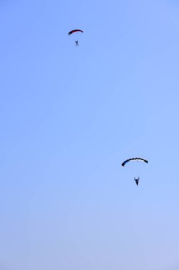 İki paraşütçü karşı mavi bir gökyüzü inerler.