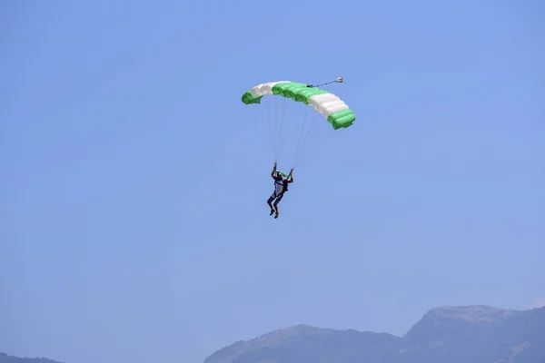 Αλεξιπτωτιστής Κατεβαίνει Κατά Έναν Μπλε Ουρανό Στο Παρασκήνιο Στα Βουνά — Φωτογραφία Αρχείου