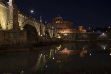 Aziz Angelo Kalesi ve yansımaları ile gece Köprü'nın güzel manzarasına Tiber Nehri üzerinde. Roma İtalya