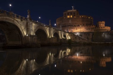 Aziz Angelo Kalesi ve yansımaları ile gece Köprü'nın güzel manzarasına Tiber Nehri üzerinde. Roma İtalya