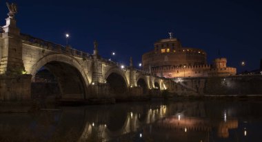 Aziz Angelo Kalesi ve yansımaları ile gece Köprü'nın güzel manzarasına Tiber Nehri üzerinde. Roma İtalya