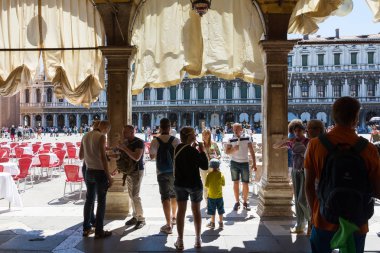 Venice, İtalya-17 Ağustos 2014:Tourists yürüyüş Piazza San Marco Venedik arcades altında sırasında güneşli bir gün.