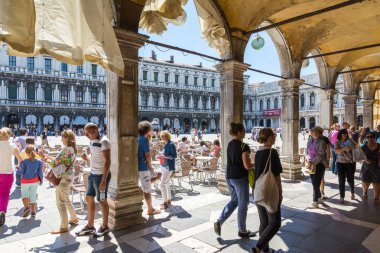 Venice, İtalya-17 Ağustos 2014:Tourists yürüyüş Piazza San Marco Venedik arcades altında sırasında güneşli bir gün.