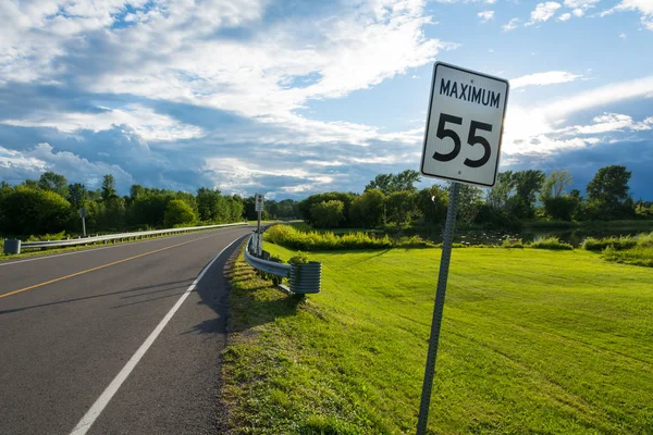 speed limit sign in the green of the Canadian countryside with a storm on the horizon