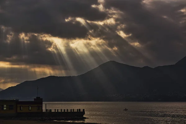 秋の日の終わりの湖に雲の切れ間から太陽の光 — ストック写真