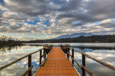 Varese Gölü sonbahar günbatımı, bulutlu gökyüzü ile iskelede