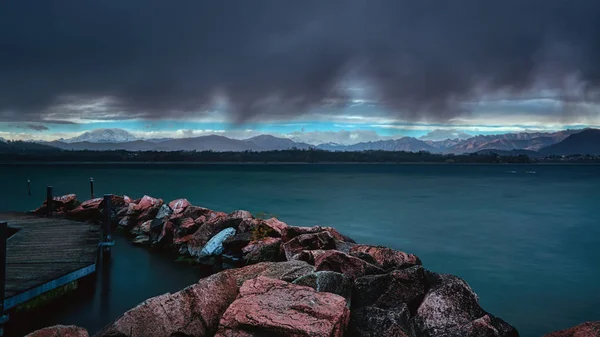 手前に石の壁がある湖の上に嵐の雲 — ストック写真