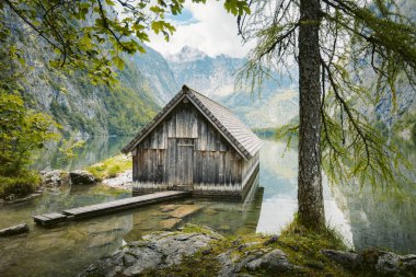 Yaz aylarında mavi gökyüzü ve bulutlar ile güzel bir güneşli bir günde doğal Obersee Gölü'nde geleneksel eski ahşap tekne evi Pastoral görünümü, Millipark Berchtesgadener Land, Bavyera, Almanya