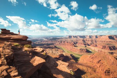 Genç bir erkek yürüyüşçü, ünlü Colorado Nehri ve güzel Kanyonlar Ulusal Parkı manzaralı Ölü At Noktası Eyalet Parkı Utah 'ta dramatik bir manzaranın tadını çıkarıyor.