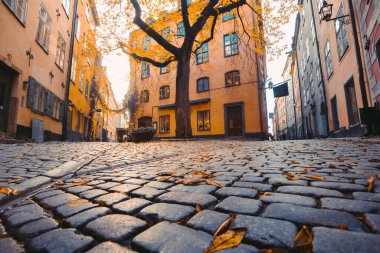 İsveç 'in Gamla Stan Old Town semtinde gün batımında güzel altın gece ışığında eski renkli evlerin olduğu büyüleyici Stockholm sokak sahnesi