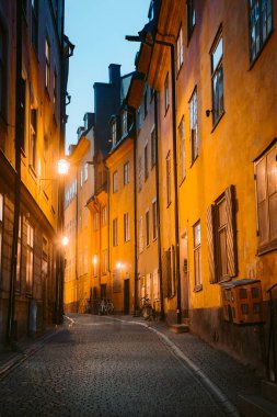 Stockholm 'ün tarihi Gamla Stan' inin (Eski Şehir) Stockholm merkez Stockholm, İsveç 'te alacakaranlıkta mavi saatte aydınlattığı güzel sokaktaki geleneksel evlerin klasik alacakaranlık manzarası.