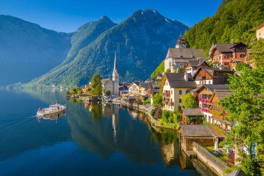 Scenic picture-postcard view of famous Hallstatt mountain village in the Austrian Alps with passenger ship in beautiful morning light on a sunny day in summer, Salzkammergut region, Austria clipart