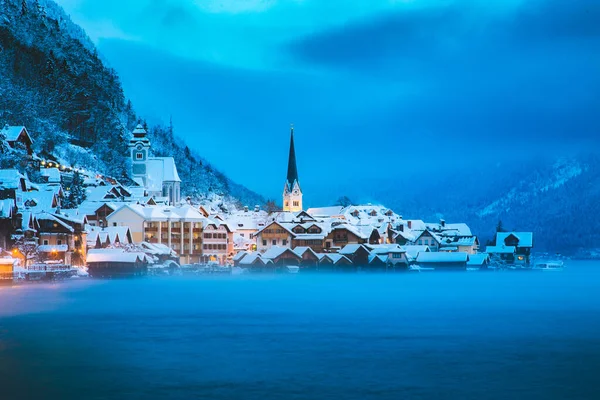 冬の美しい寒い霧の日の夜明けの青い時間の間に神秘的な夕暮れのアルプスの有名なハルシュタット湖畔の町のパノラマビュー ザルツカマーグート地域 オーストリア — ストック写真