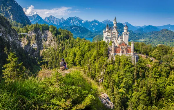 険しい崖からの景色を楽しむ男性観光客と有名なノイシュヴァンシュタイン城の古典的な景色 フエッセン バイエルン州 ドイツ — ストック写真