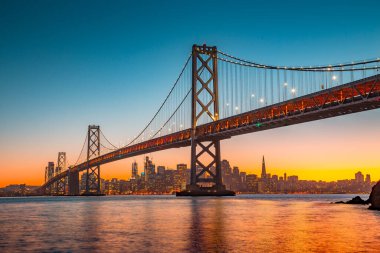 San Francisco 'nun klasik panoramik manzarası ünlü Oakland Bay Köprüsü yazın gün batımında güzel bir altın akşam ışığı ile aydınlandı, San Francisco Körfez Bölgesi, Kaliforniya, ABD