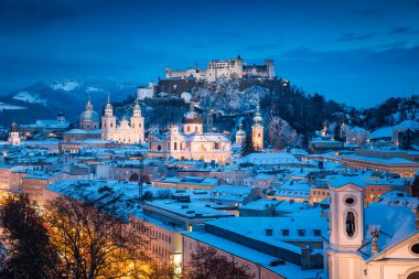 Ünlü Festung Hohensalzburg ve Salzach nehri ile tarihi Salzburg şehrinin klasik manzarası. Kış aylarında güzel bir alacakaranlıkla aydınlanıyor. Salzburger Diyarı, Avusturya.