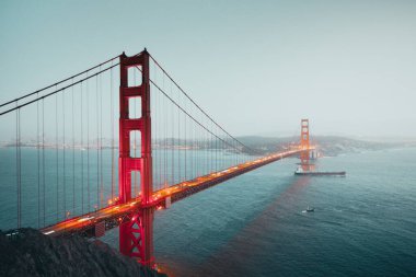 Ünlü Golden Gate 'in klasik panoramik manzarası. Güneş battıktan sonra güzel bir kargo gemisi. Yazın alacakaranlıkta, San Francisco, Kaliforniya, ABD' de.
