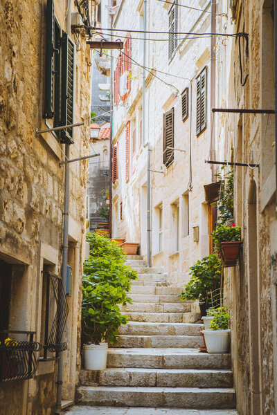 Scenic vertical view of small alleyway in an old town in Europe with golden light in summer