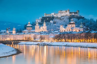 Ünlü Festung Hohensalzburg ve Salzach nehri ile tarihi Salzburg şehrinin klasik manzarası. Kış aylarında güzel bir alacakaranlıkla aydınlanıyor. Salzburger Diyarı, Avusturya.