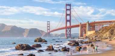 Ünlü Golden Gate Köprüsü 'nün panoramik manzarası Baker Sahili' nden gün batımında güzel altın bir akşam ışığı altında mavi gökyüzü ve bulutlarla yaz mevsiminde, San Francisco, California, ABD