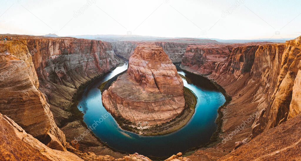 Classic wide-angle view of famous Horseshoe Bend, a horseshoe-shaped meander of the Colorado River located near the town of Page, in beautiful golden evening light at sunset in summer, Arizona, USA