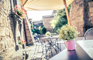 Avrupa 'nın eski bir caddesinde eski tip Instagram tarzı filtre efektli masa ve sandalyeli kafe