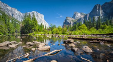 Classic view of scenic Yosemite Valley with famous El Capitan rock climbing summit and idyllic Merced river on a sunny day with blue sky and clouds in summer, Yosemite National Park, California, USA clipart