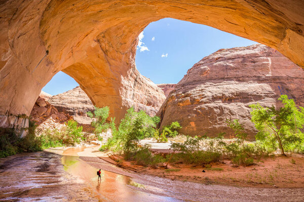 Wide angle view of a hiker backpacking beneath stunning Jacob Hamblin Arch in Coyote Gulch, Grand Staircase - Escalante National Monument, Utah, USA