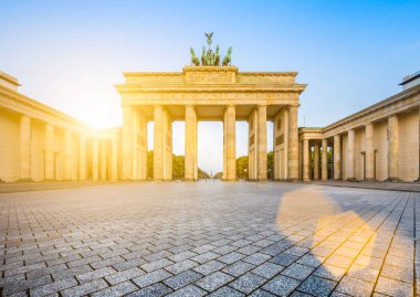 Ünlü Brandenburger Tor (Brandenburg Kapısı), Almanya 'nın en tanınmış simgelerinden ve ulusal sembollerinden biridir, güneşin doğuşunda güzel altın bir sabah ışığı altında, mercek efektiyle, Berlin, Almanya