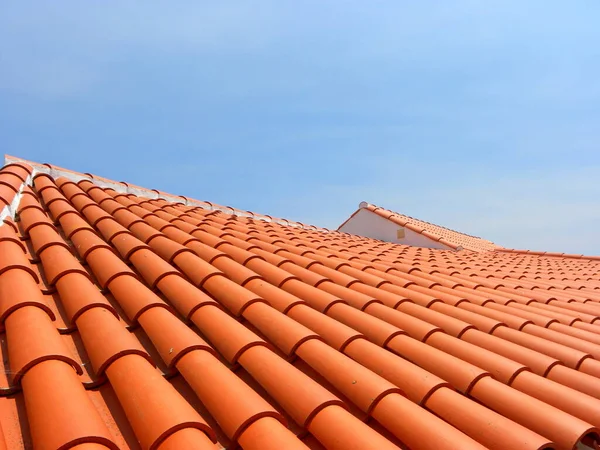 Red tile roof under blue sky. The photo is divided in half. One part is a roof made of clay tiles and the other is a pure blue sky. — Stock Image Red Tile Roof Blue Sky Photo Divided Half One Part Royalty Free Stock Photos