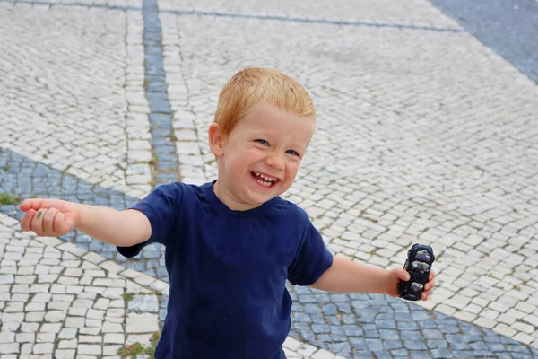 Çekici sarışın bir çocuğun portresi. Üç yaşında bir çocuk kolları açık yürür ve gülümser. Mutlu çocuk.