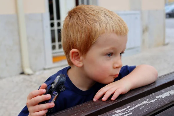 Çekici sarışın bir çocuğun portresi. Üç yaşında bir çocuk elini uzatıyor ve mesafeye bakıyor. Ciddi çocuk.