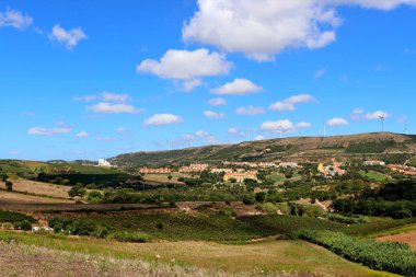 Portekiz 'in doğal manzarasının muhteşem panoramik manzarası. Mavi gökyüzü, yüksek tepeler, rüzgar türbinleri ve geleneksel seramik kiremitli çatı evleri