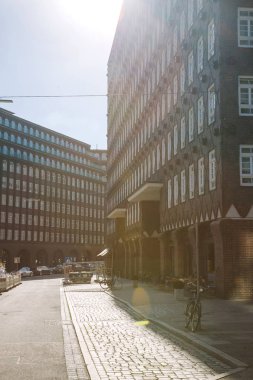 HAMBURG, GERMANY - 28 JUNE 2018: bicycles on street with sunlight, people sitting in cafes clipart