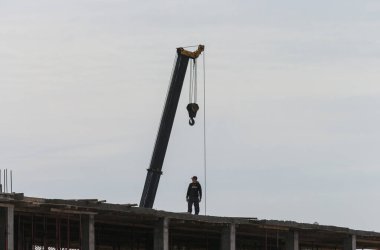 Uralsk, Kazakistan (Kazakistan), 24,05.2020: inşaat vinci ve insan silueti, vinç altında çalışan işçi, inşaat, inşaat alanında tehlike