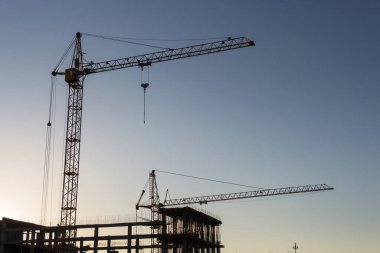 Gün batımında gökyüzüne karşı kule vinçleri