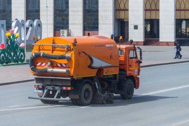 Sweeper sweeps the road in the city. Clean city. Cleaning of roads on the KAMAZ car. Orange special equipment