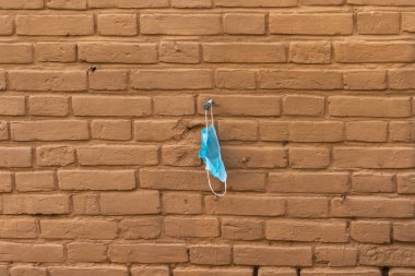 Kullanılmış bir tıbbi maske duvarda asılı..