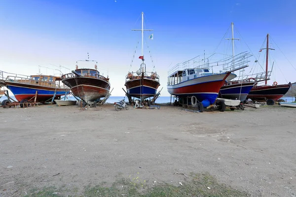 Local wooden boats for touristic purposes stranded on the beach for maintenance services while waiting on boat trailers for the summer season. Cirali-Lycian coast-Kemer distr.-Antalya province-Turkey.