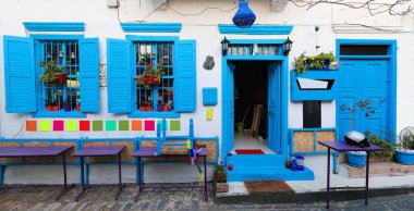 Mavi boyalı ahşap pencere panjur ve kapı ve bir beyaz duvarlı eski-merkez alan bir sokakta bina mor tabloları. Kaş ya da eski Antiphellos şehri-Antalya ili-Türkiye.