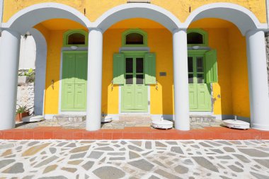 Üçlü ile neoklasik stili-sarı ev ağ geçidi ve ışık yeşil boyalı kapı ve Panjur Pera Meria bölge-W.side liman içinde arcaded. Kastellorizo veya Megisti-Dodecanese-Rodos trafiğe çıkış-Yunanistan.
