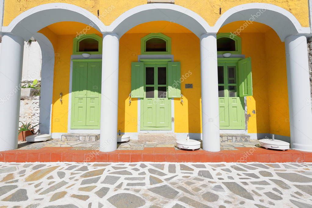 Neoclassic style-yellow house with triple arcaded gateway and light green painted doors and shutters in Pera Meria district-W.side of the harbor. Kastellorizo or Megisti-Dodecanese-Rhodes reg.-Greece.