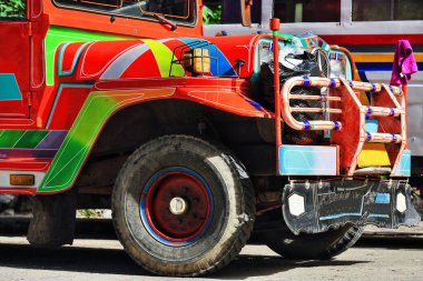 Filipinli turuncu-kırmızı dyipni-jeepney araba. Sagada 'daki toplu taşıma orijinal olarak 2. Dünya Savaşı' ndan kalma Amerikan askeri arabalarından yapılmış. Şimdi ise Japon fazlalıklarından yerel olarak değiştirilmiş. Igorot-Filipinler.